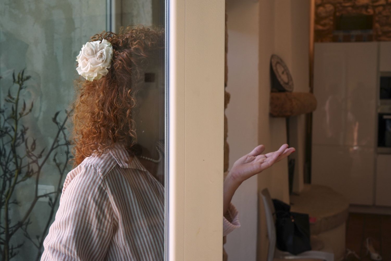 Sposa con una rosa bianca tra i capelli ricci, riflessa nel vetro